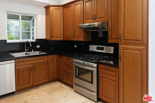 a kitchen with granite countertop stainless steel appliances a stove sink and cabinets
