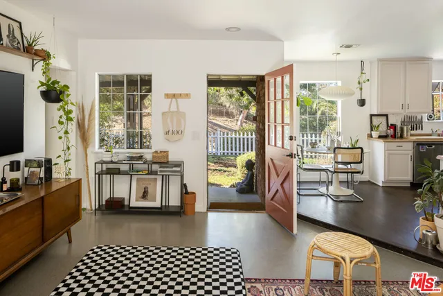 a living room with stainless steel appliances furniture a rug and a view of kitchen