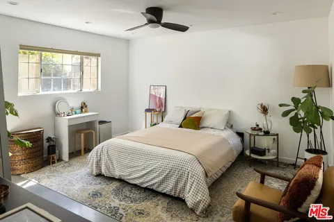 a bedroom with a bed and a potted plant on a dresser