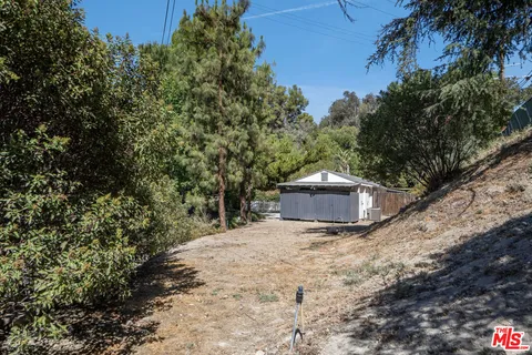 a view of a house with a yard and large trees