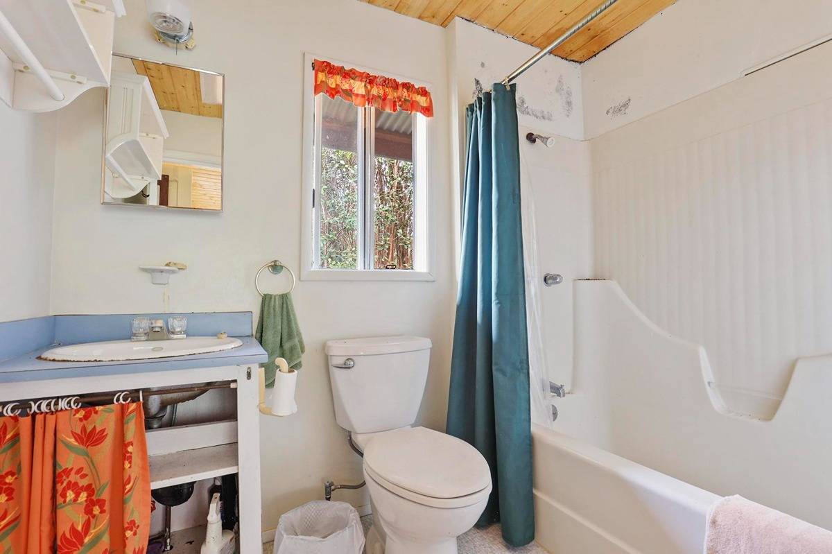 16-1585 Hopue Road, Unit 2 Mountain View, HI 96771 - Photo 23 of 29 a bathroom with a granite countertop toilet sink and mirror