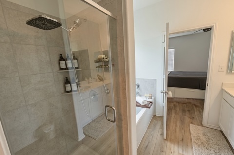 208 Wolf Springs Road Georgetown, TX 78628 - Photo 16 of 32 Luxurious shower with a rainfall head and a deep soaking tub, complemented by warm wood flooring.