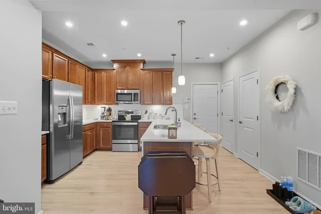 a kitchen with stainless steel appliances granite countertop a refrigerator a sink dishwasher and a stove with wooden floor