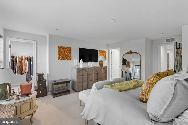 a bedroom with bed a flat tv screen and dresser