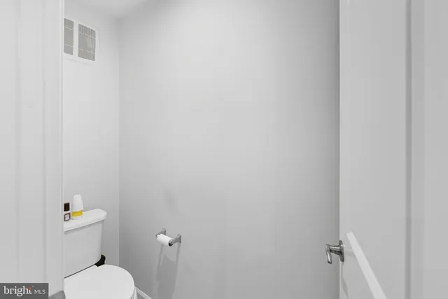 a white toilet sitting next to a white wall