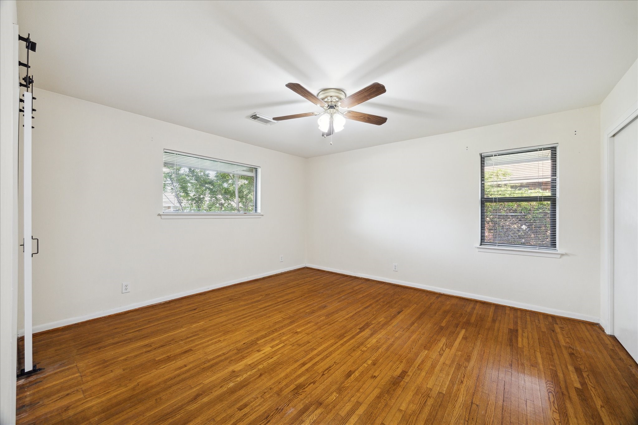 8907 Autauga Street Houston, TX 77080 - Photo 11 of 20 Bright and airy bedroom with hardwood floors, two windows for natural light, and a ceiling fan for comfort. Neutral walls offer a versatile space.