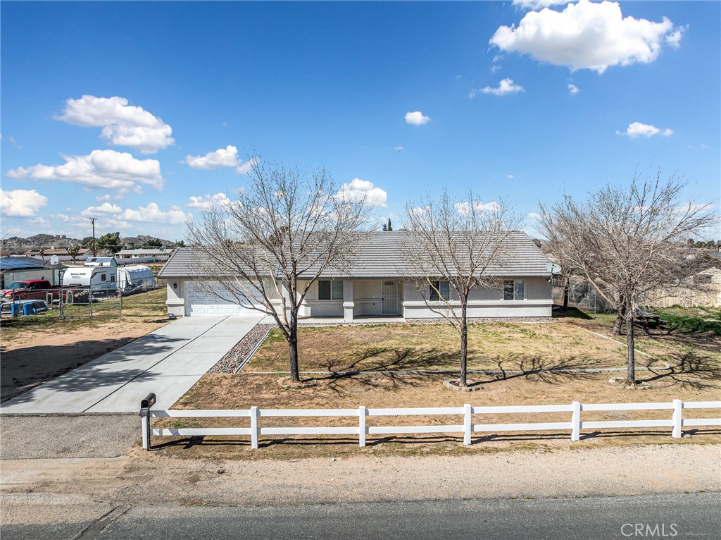 Charming single-story home on a fully fenced 1-acre lot with white vinyl fencing and expansive front yard.