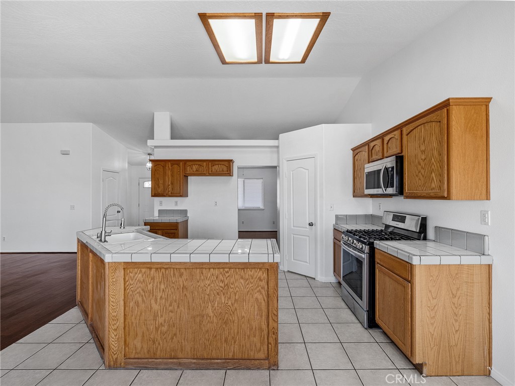14266 Kiowa Road Apple Valley, CA 92307 - Photo 11 of 27 This well-designed kitchen offers rich wood cabines, a generous pantry for extra storage, stainless steel appliances, and plenty of counter space for meal preparation.
