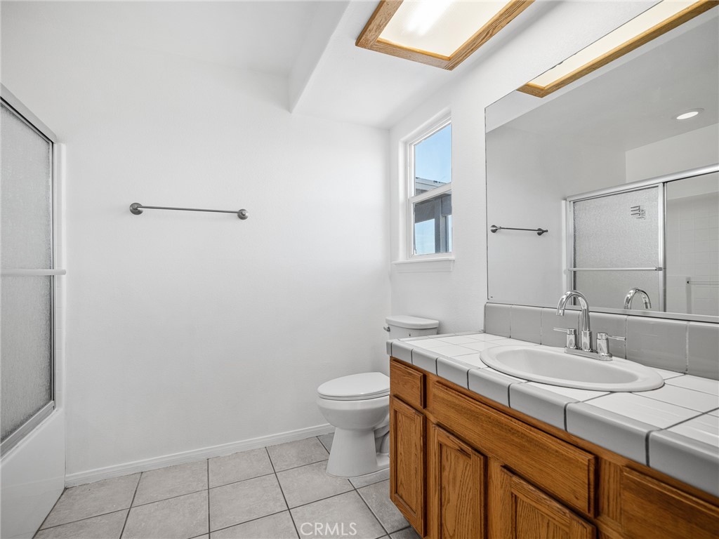 14266 Kiowa Road Apple Valley, CA 92307 - Photo 17 of 27 Well-maintained bathroom with tile countertops, ample cabinet storage, and shower/tub combo.