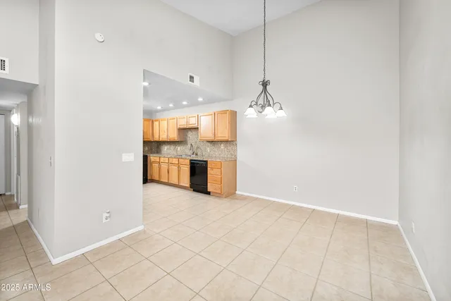 a dining room with furniture a chandelier and kitchen view