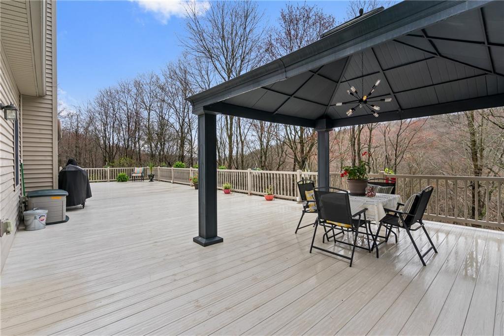 4275 Burtner Road Natrona Heights, PA 15065 - Photo 25 of 42 a view of a roof deck with table and chairs under an umbrella with wooden floor
