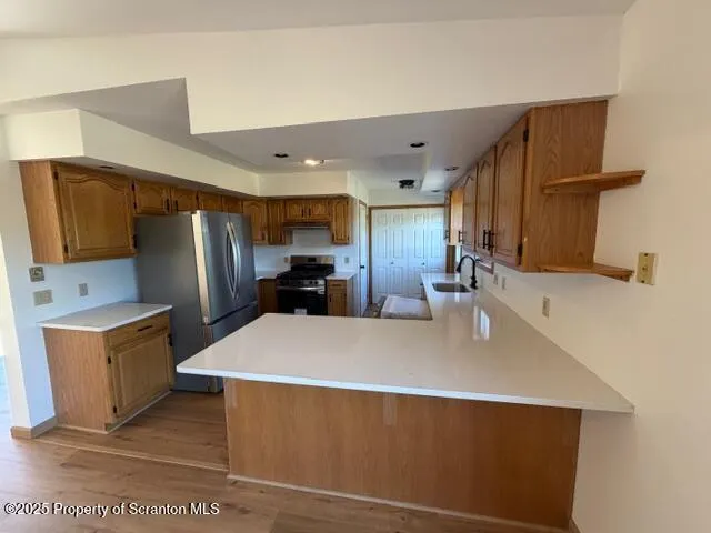 a large kitchen with stainless steel appliances a refrigerator a sink a stove top oven and a counter space