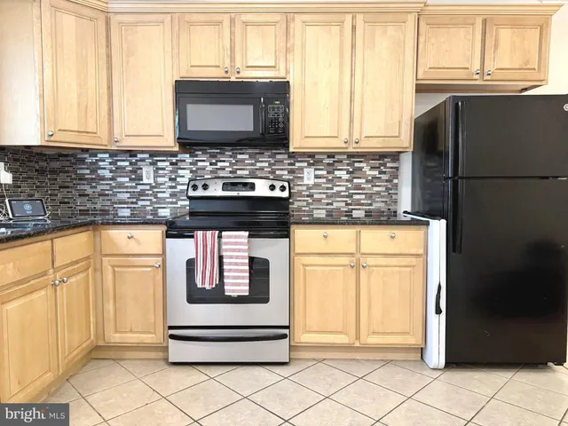 a kitchen with granite countertop white cabinets and black appliances