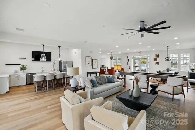 a living room with furniture kitchen view and a wooden floor