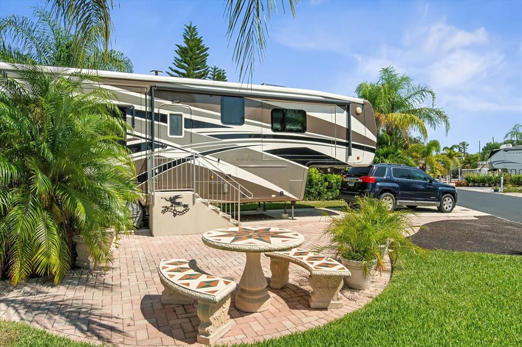 2911 Birdie Drive, Unit 85 Bowling Green, FL 33834 - Photo 7 of 16 a view of a patio with table and chairs potted plants and palm tree