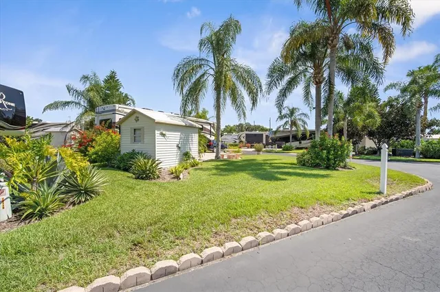 a view of a house with a yard and palm trees