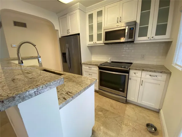 a kitchen with stainless steel appliances granite countertop a stove microwave and refrigerator