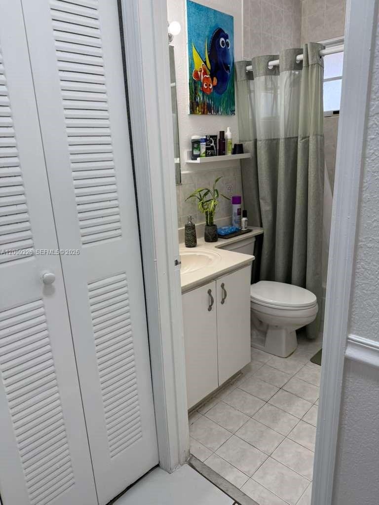 3514 West 76th Street, Unit 203 Hialeah, FL 33018 - Photo 36 of 39 a bathroom with a sink a toilet and a shower curtain