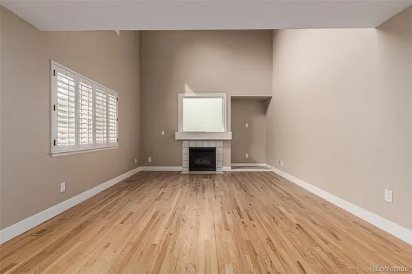 an empty room with wooden floor a fireplace and windows
