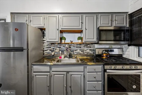 a kitchen with stainless steel appliances granite countertop a refrigerator sink stove microwave and cabinets