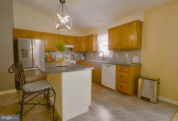 a kitchen with stainless steel appliances granite countertop a sink a stove cabinets dining table and chairs