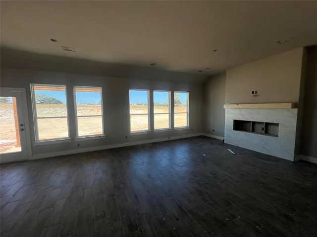 an empty room with wooden floor fireplace and windows
