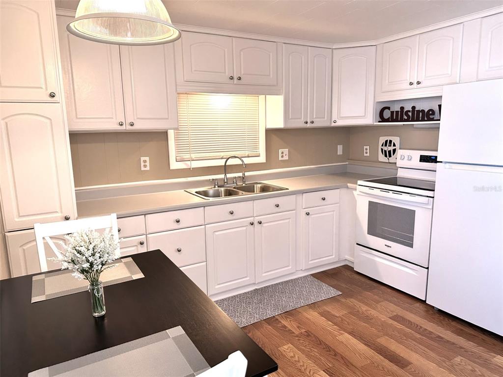 1600 Old Coachman Rd., Unit 816 Clearwater, FL 33765 - Photo 17 of 26 a kitchen with a sink dishwasher a stove and white cabinets with wooden floor
