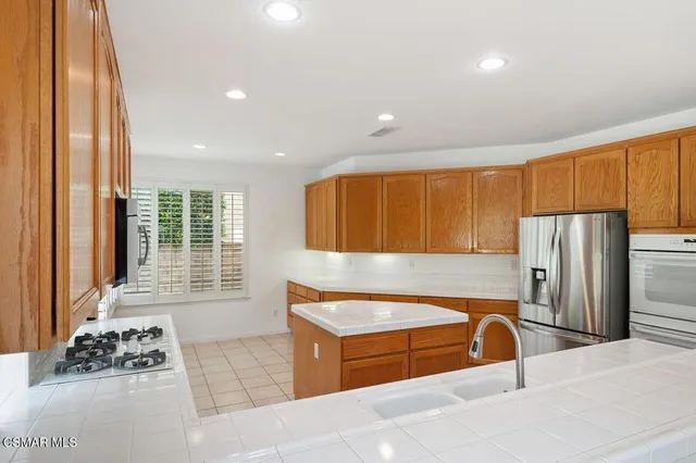 a kitchen with stainless steel appliances kitchen island granite countertop a refrigerator and a sink