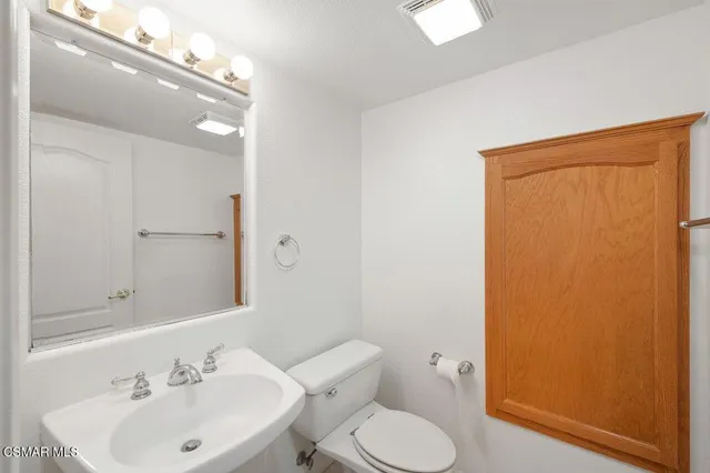 a bathroom with a toilet a sink and mirror