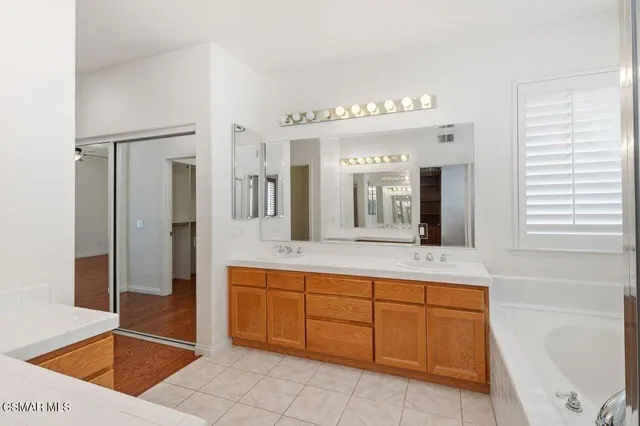 a spacious bathroom with a tub sink and mirror