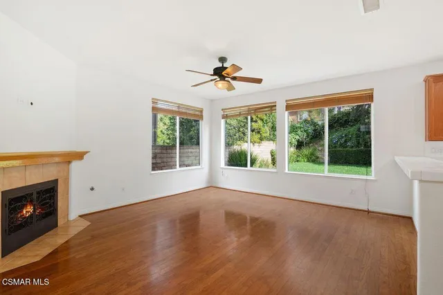 a view of an empty room with wooden floor and a fireplace