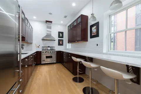 a kitchen with stainless steel appliances a sink a stove a microwave a refrigerator and cabinets