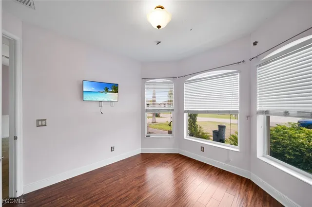 a view of an empty room with window and wooden floor