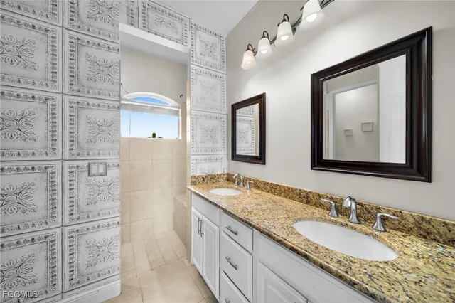 a bathroom with a granite countertop double vanity sink and mirror