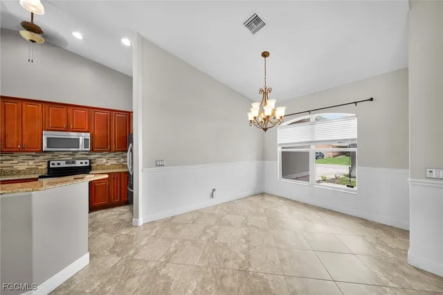 a view of an empty room with kitchen and a window