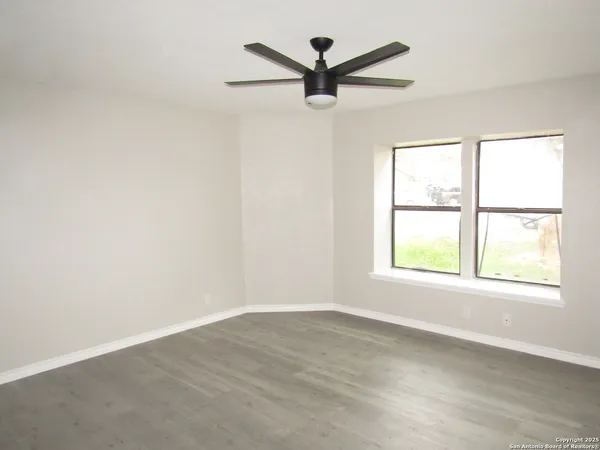 an empty room with a window and a fan