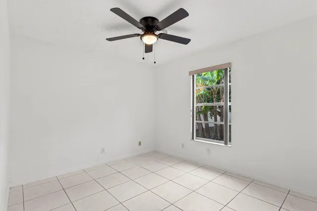 an empty room with windows and ceiling fan