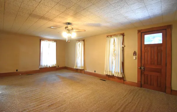 an empty room with windows and ceiling fan