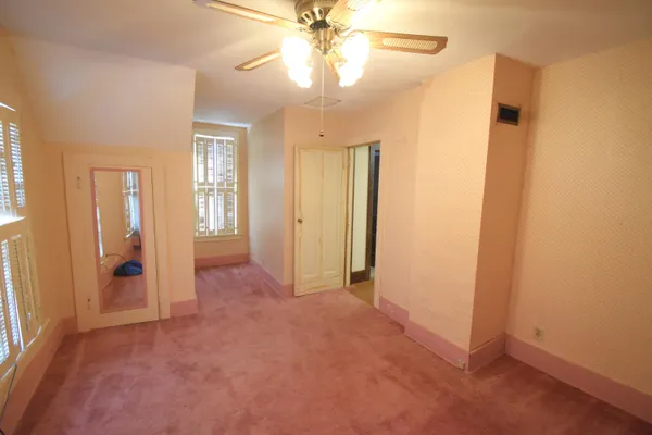 an empty room with closet and a chandelier fan