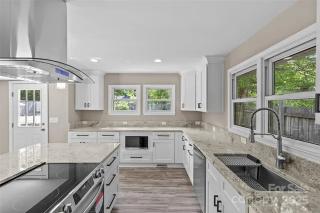 a kitchen with stainless steel appliances granite countertop hardwood floor sink stove and granite counter top