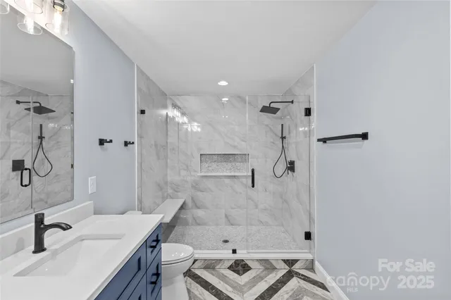 a bathroom with a granite countertop sink a toilet and shower