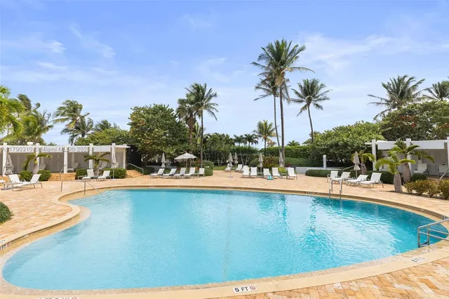 a view of a swimming pool with a lawn chairs under an umbrella