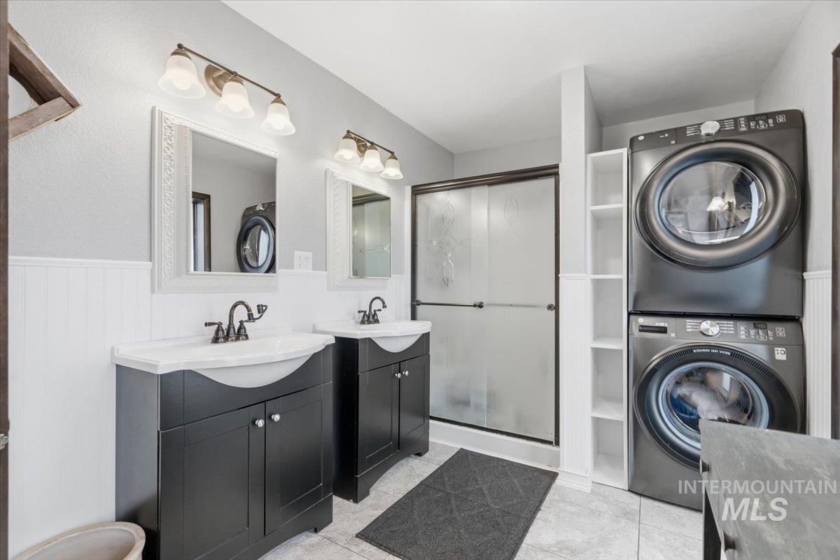 7771 Elmore Road Fruitland, ID 83619 - Photo 14 of 45 Master bath with two vanities, a shower stall, a wainscoted wall, stacked washer and clothes dryer.