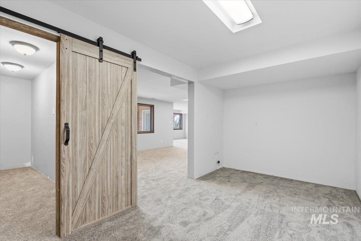 7771 Elmore Road Fruitland, ID 83619 - Photo 23 of 45 Spare room with a barn door and light colored carpet