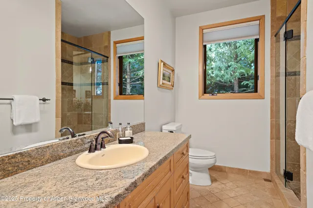 a bathroom with a granite countertop sink toilet and large mirror