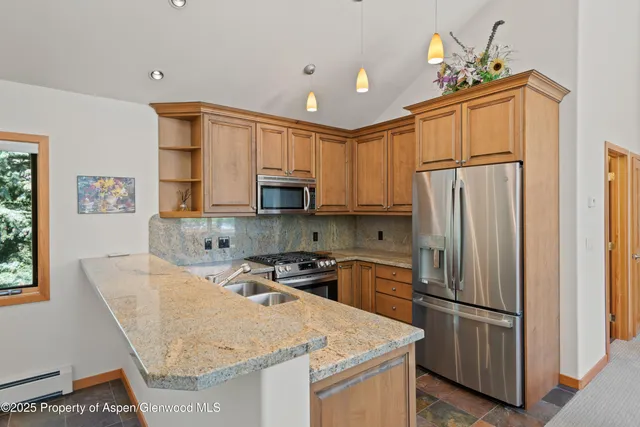 a kitchen with stainless steel appliances granite countertop a refrigerator a stove a sink dishwasher and white cabinets with wooden floor