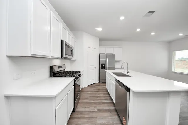 a kitchen with white cabinets appliances and sink