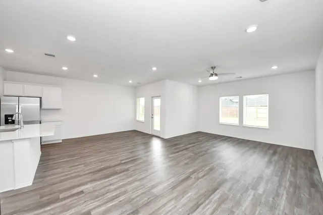 an empty room with wooden floor and windows
