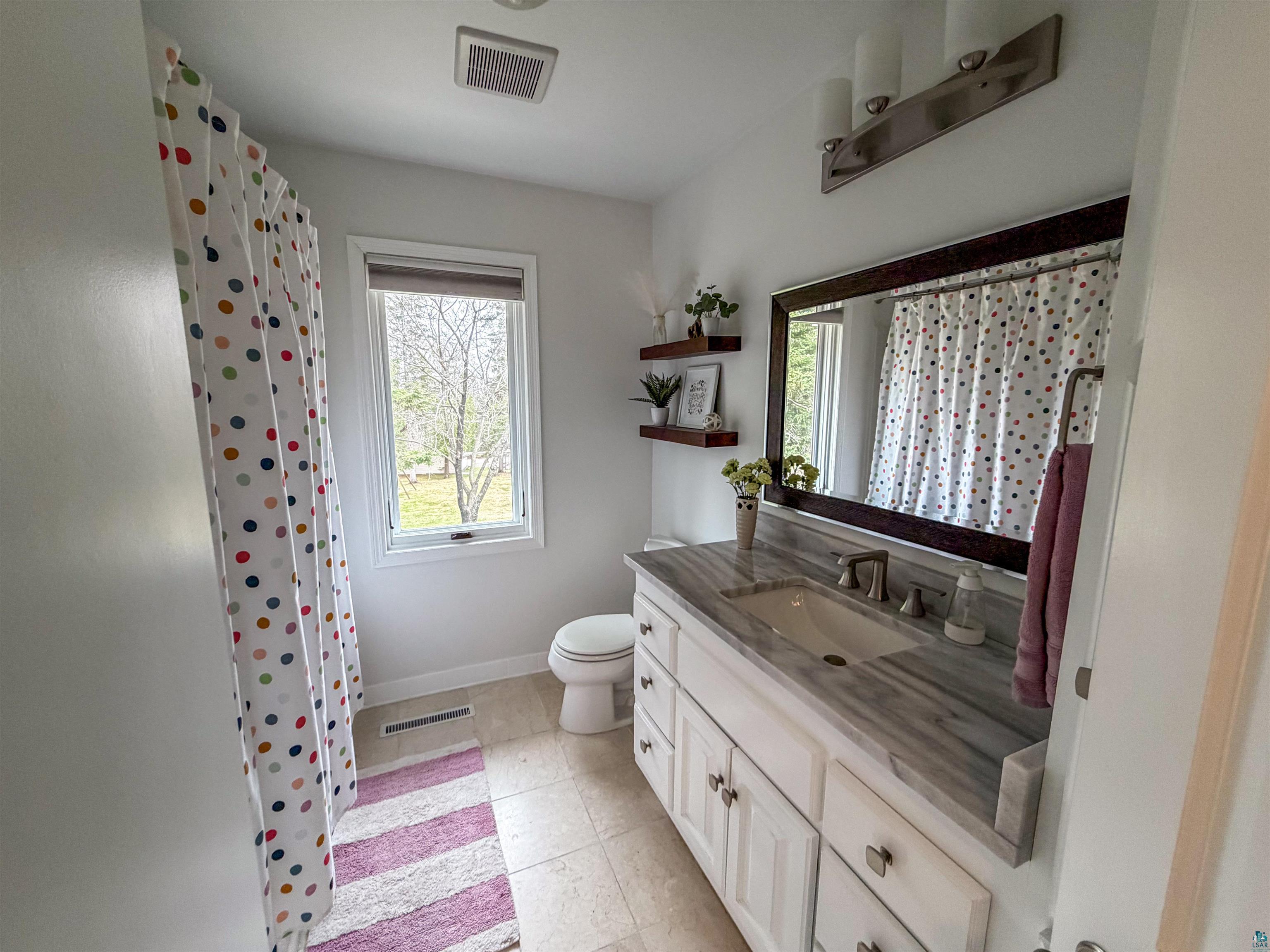 3704 Greysolon Road Duluth, MN 55804 - Photo 17 of 51 Bathroom featuring a single window, a toilet, and an extended vanity with a light-toned countertop, an undermount sink, and brushed nickel fixtures