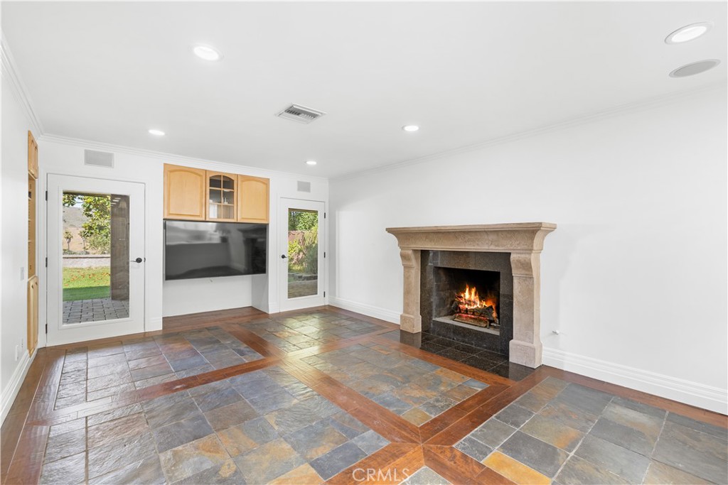 26096 Adamor Road Calabasas, CA 91302 - Photo 16 of 61 Family room with Venetian finished gas fireplace, wood and slate floor, built-in tv and stereo cabinets, and glass doors to covered patio and mountain views.